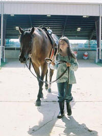 A young girl walks a horse during a previous session of Horse Camp at the ASU Equine Center.