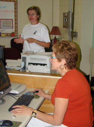 Dr. Mary Jackson Pitts, standing, provides technology instruction with Dr. Rebecca Matthews, seated, at the TEXTS workshop.